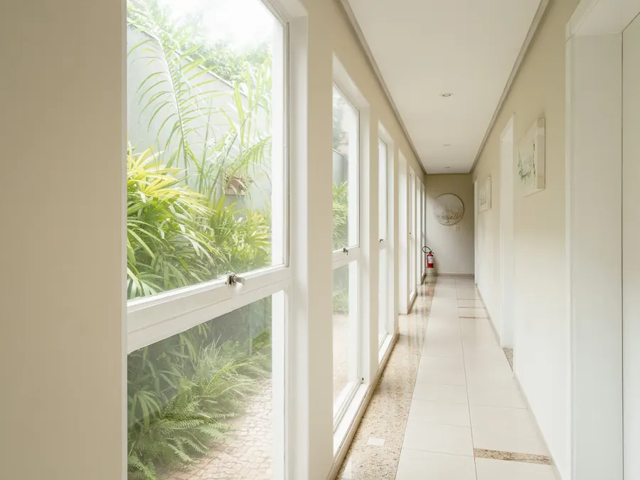 Corredor envidraçado da clínica, voltado para o jardim